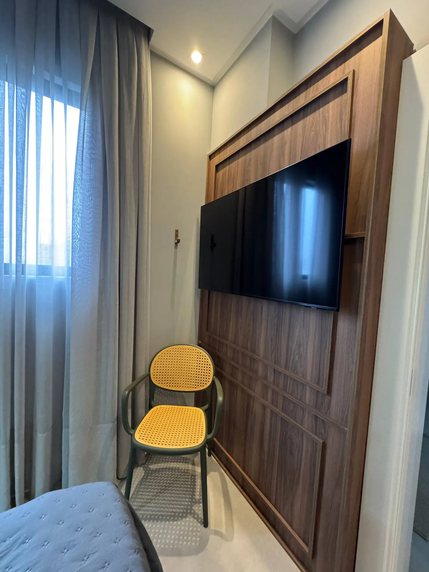 Painel de madeira com TV e cadeira amarela, visto de perto