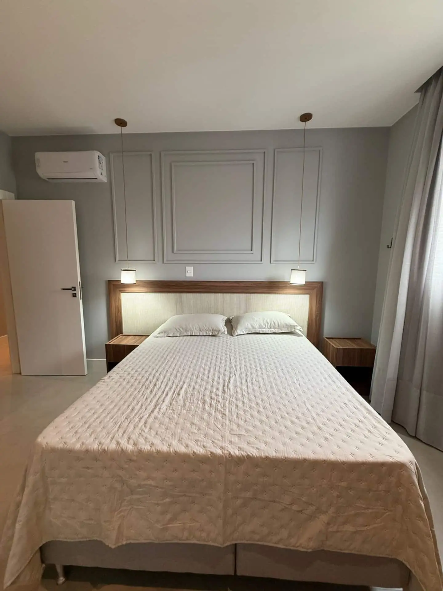 Cama de casal com cabeceira estofada e ar-condicionado na parede
